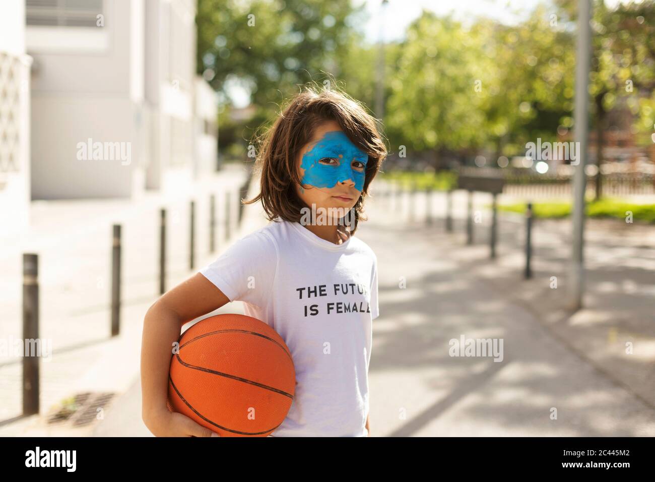 Portrait of boy with painted blue mask on his face holding basketball Stock Photo