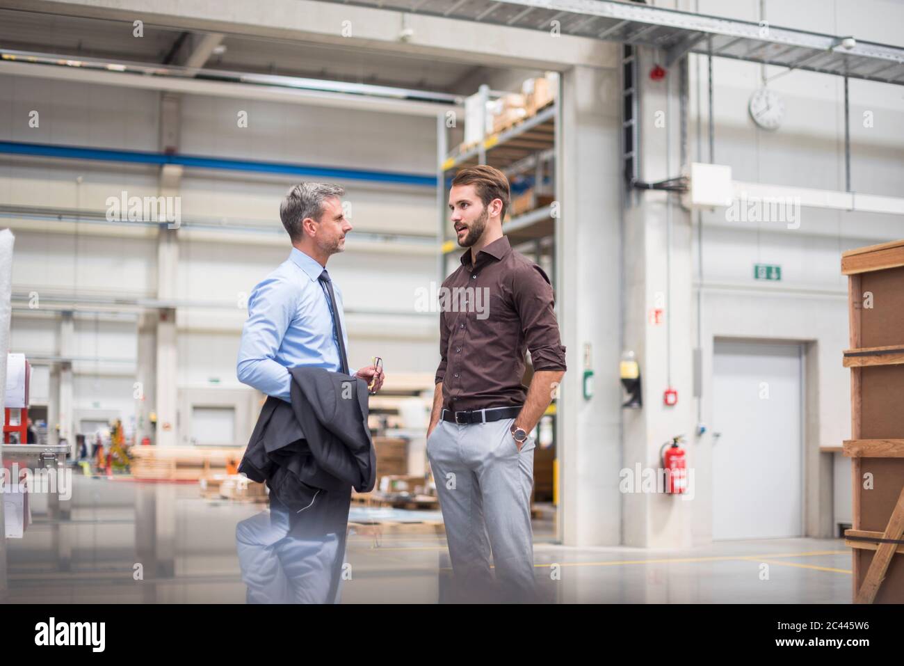 Two businessmen talking in a factory Stock Photo - Alamy