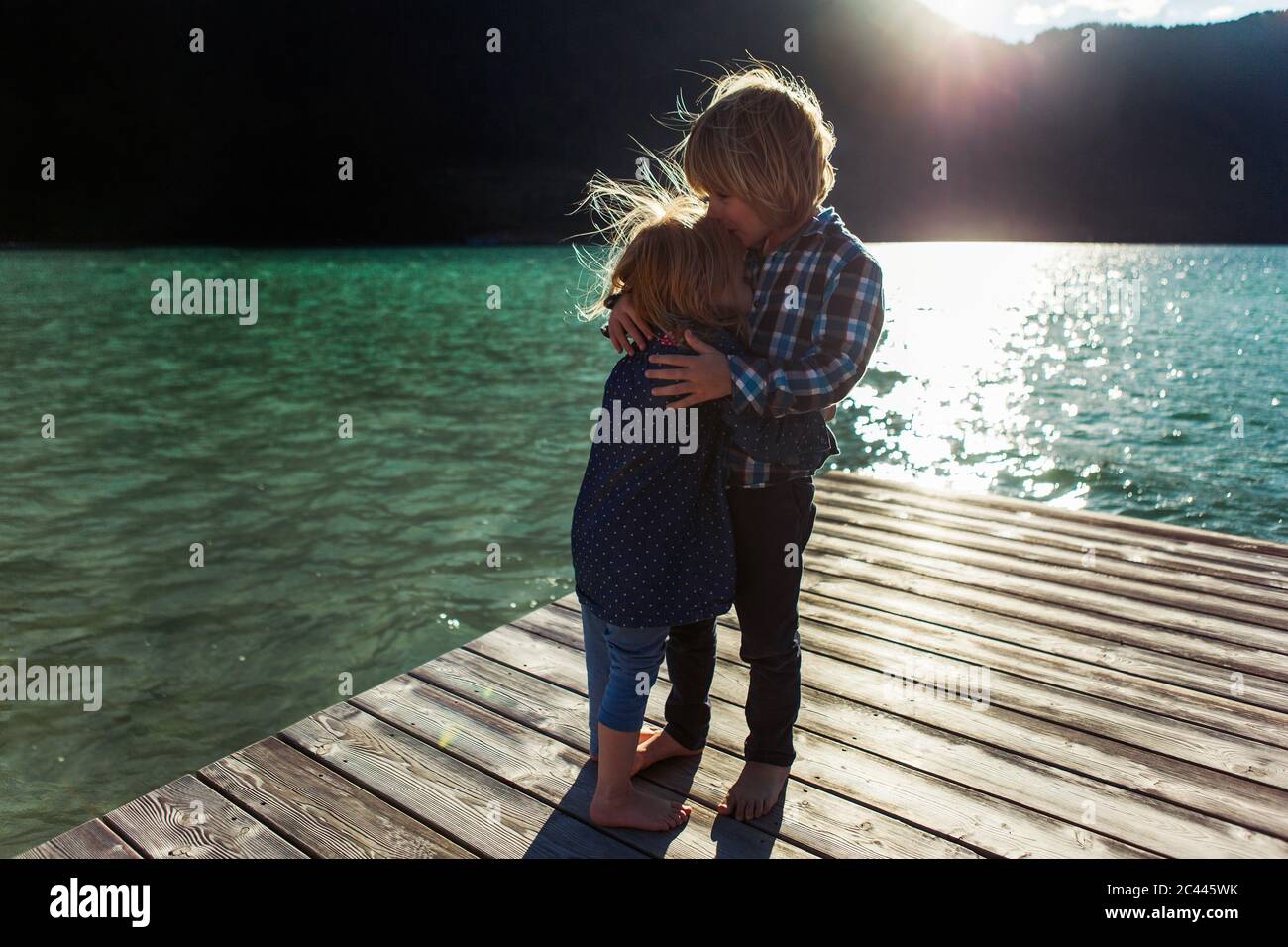 Brother kissing sister while standing on boardwalk at Achensee, Tyrol State, Austria Stock Photo