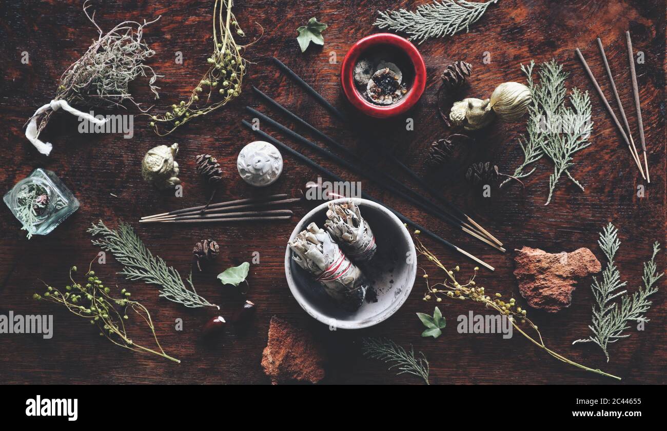 Air element objects to use in witchcraft and wicca on a witch's altar filled with evergreens, dried herbs, sage, incense sticks for smoke cleansing Stock Photo