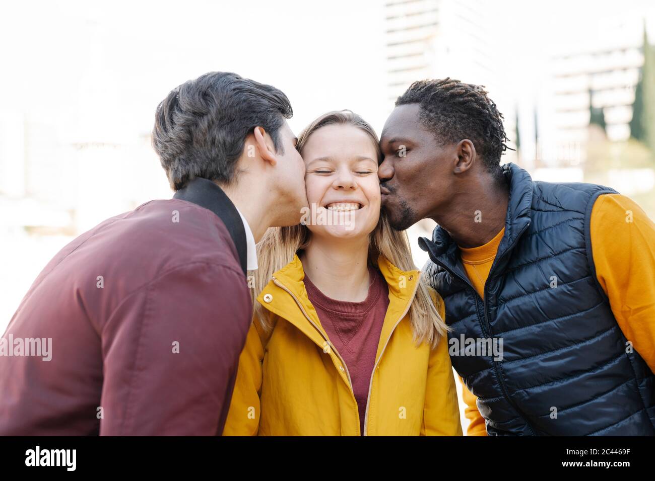 Two young men kissing smiling young woman outdoors Stock Photo - Alamy