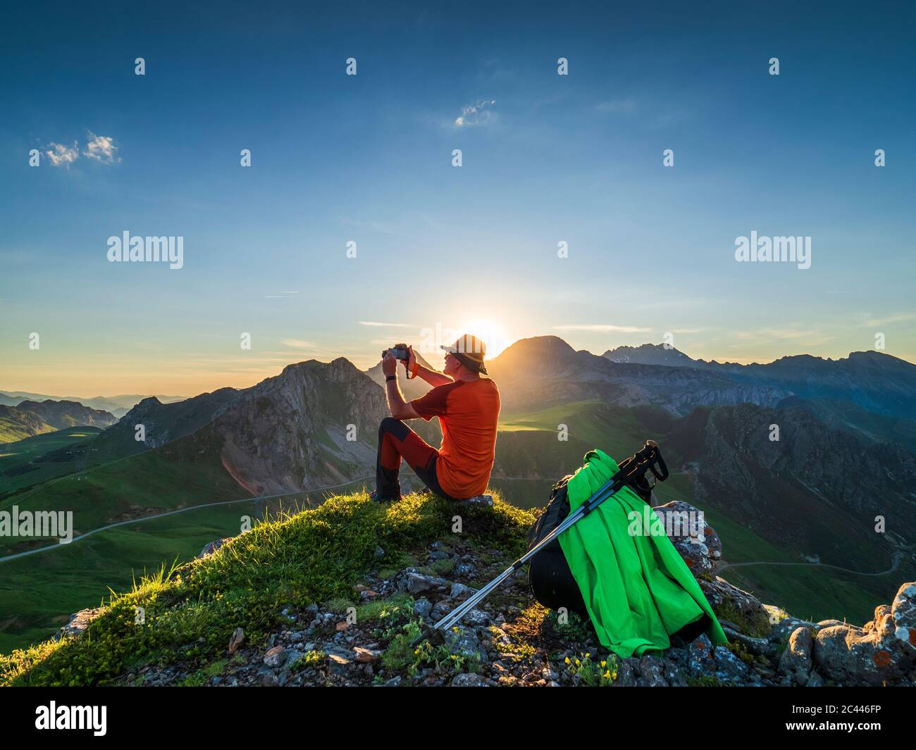 Side view of senior man photographing while sitting on mountain pass, Asturias, Spain Stock Photo
