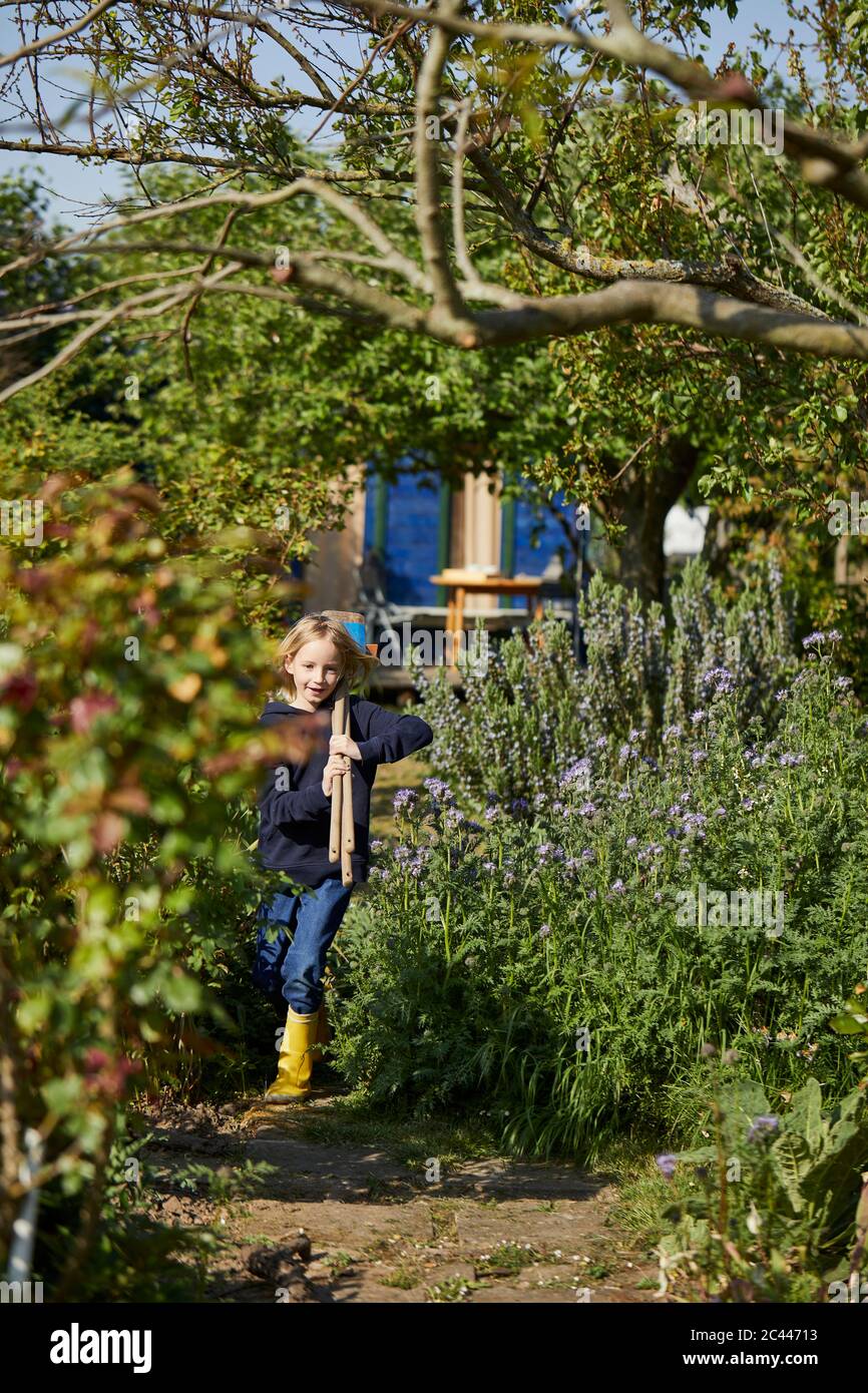 Girl in allotment garden carrying tools Stock Photo