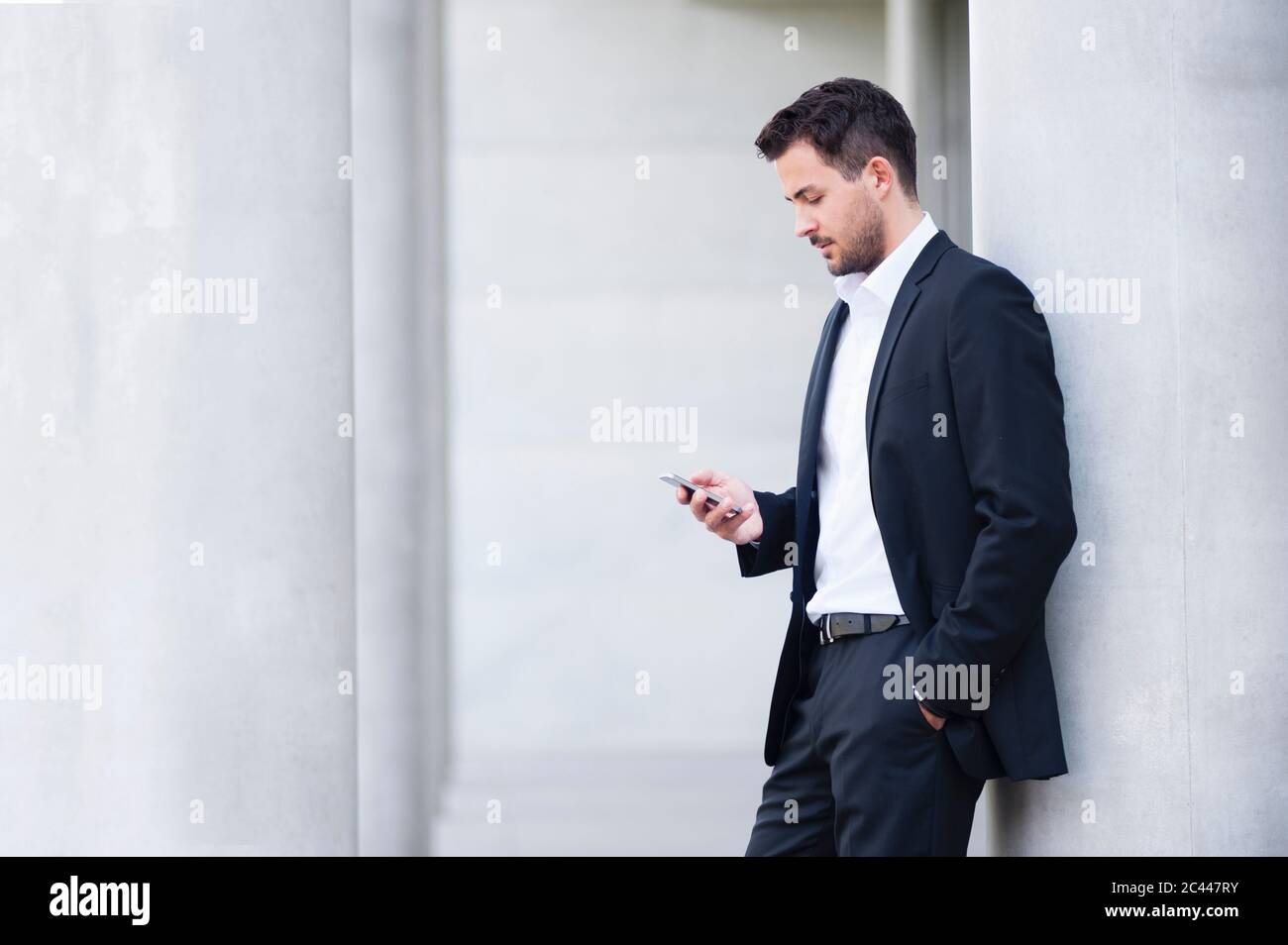 Businessman wearing suit looking on smartphone Stock Photo