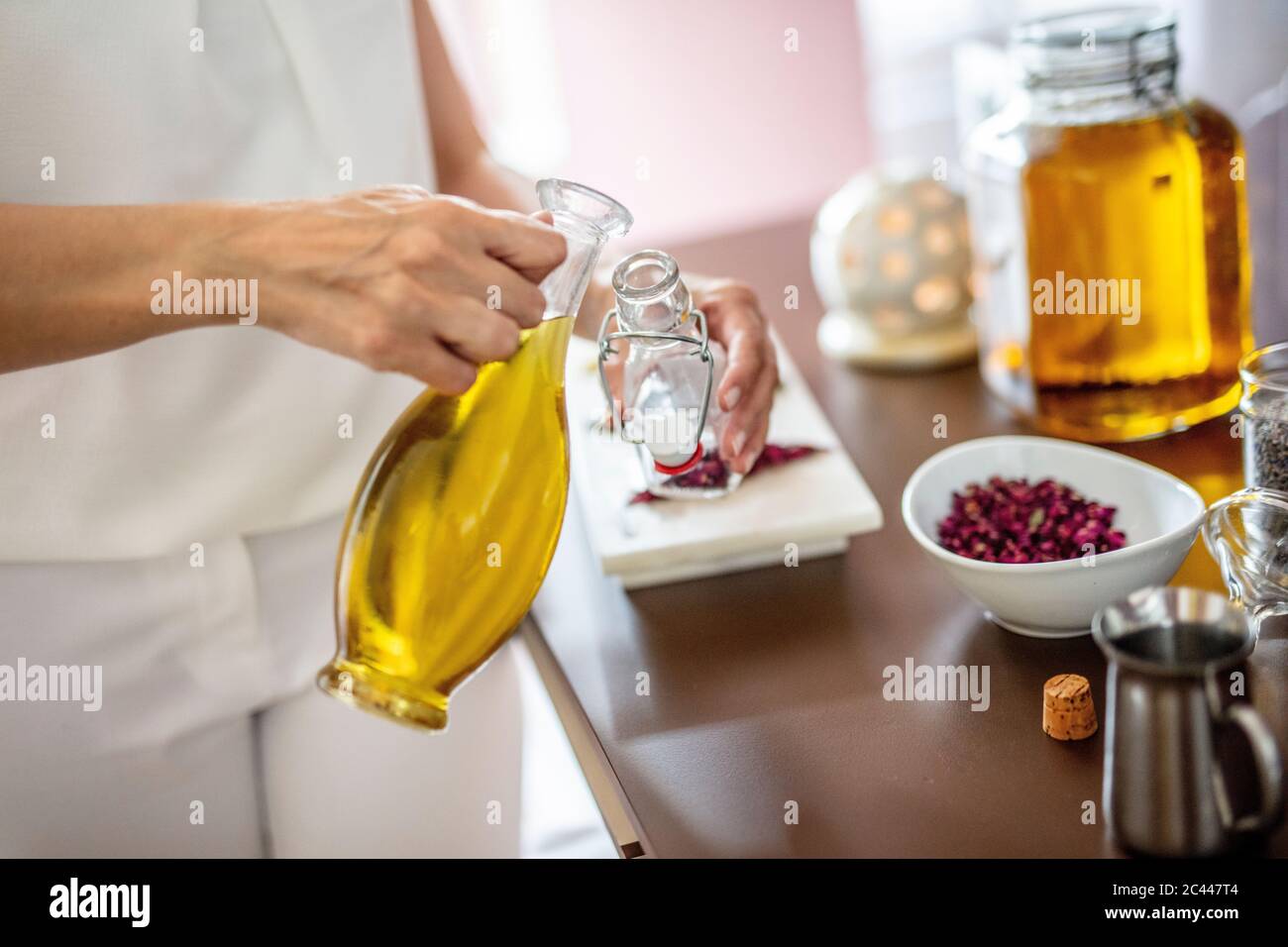 Austria, Mid section of adult woman mixing herbs with massage oil Stock Photo