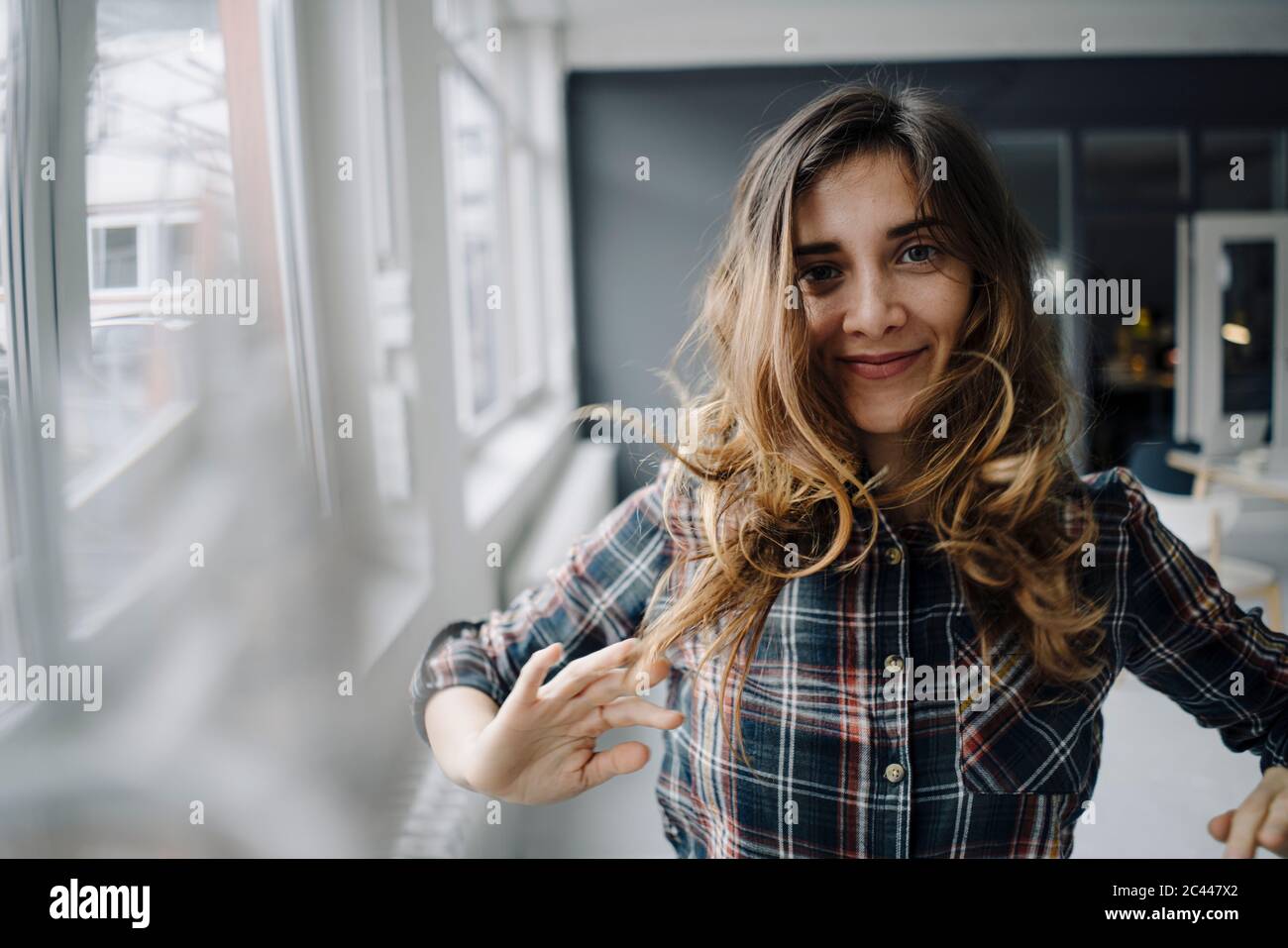 Portrait of smiling young woman dancing in a loft Stock Photo