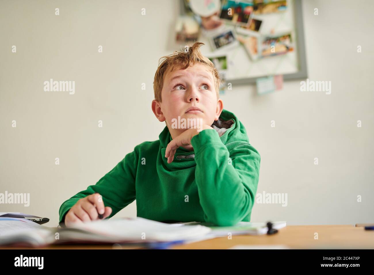 Pensive boy looking away while studying at home Stock Photo