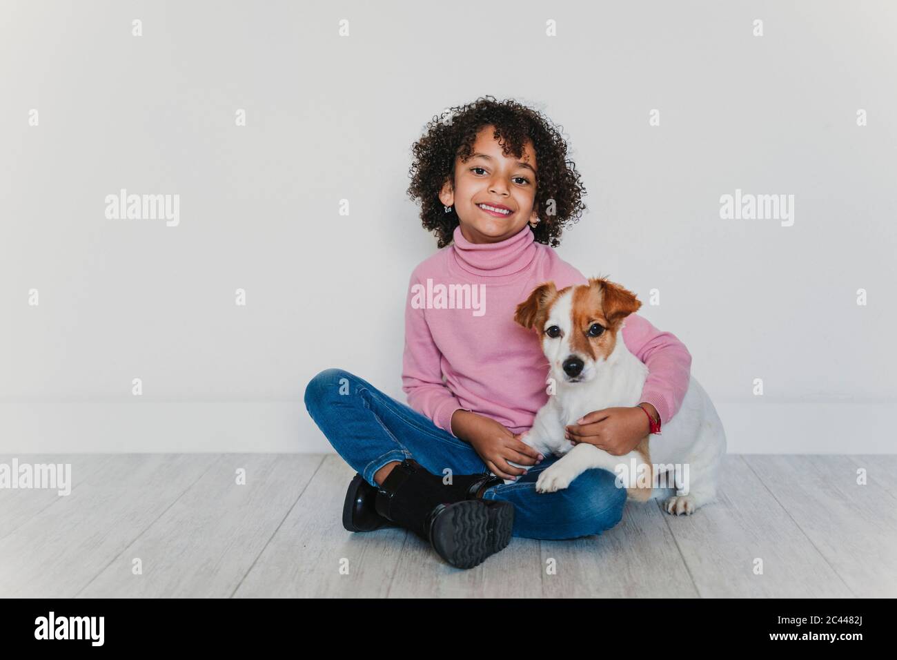 Portrait of smiling little girl sitting on the floor with her dog Stock ...