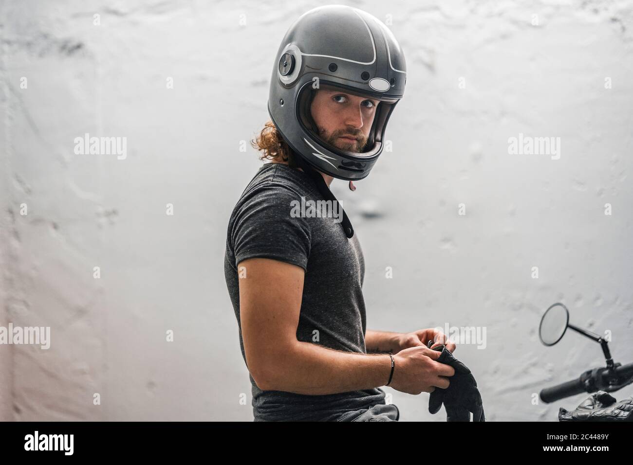 Young man putting on his gloves sitting on motorcycle Stock Photo