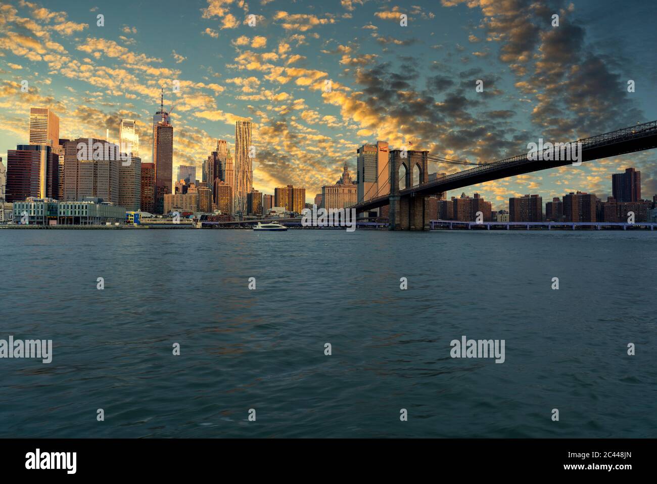 USA, New York, New York City, East River and Brooklyn Bridge at dramatic sunrise with Manhattan skyline in background Stock Photo
