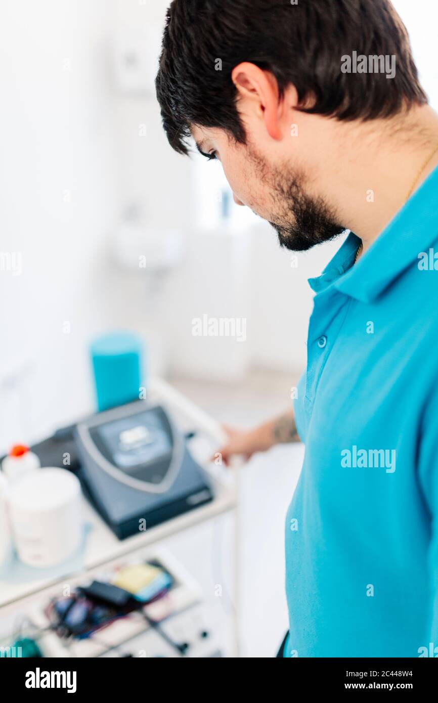 Visually impaired physiotherapist using electro stimulation machine in clinic Stock Photo