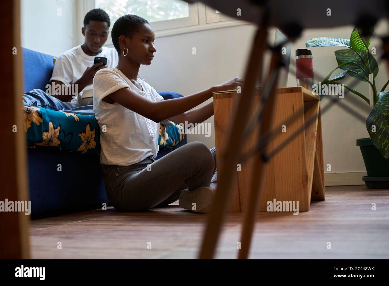 Young couple using smartphone and laptop at home Stock Photo