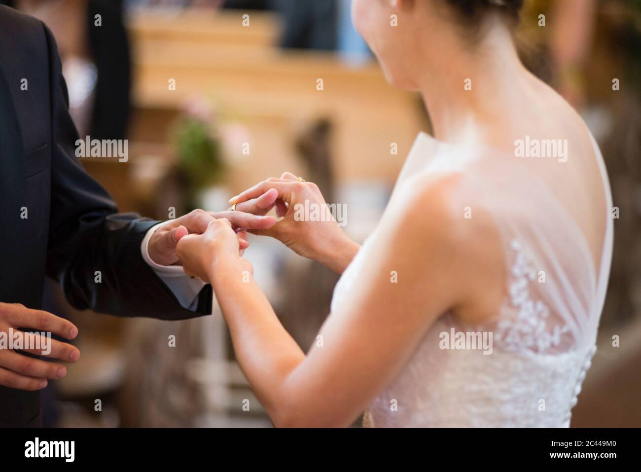Bride wearing wedding ring to bridegroom while standing in church Stock Photo