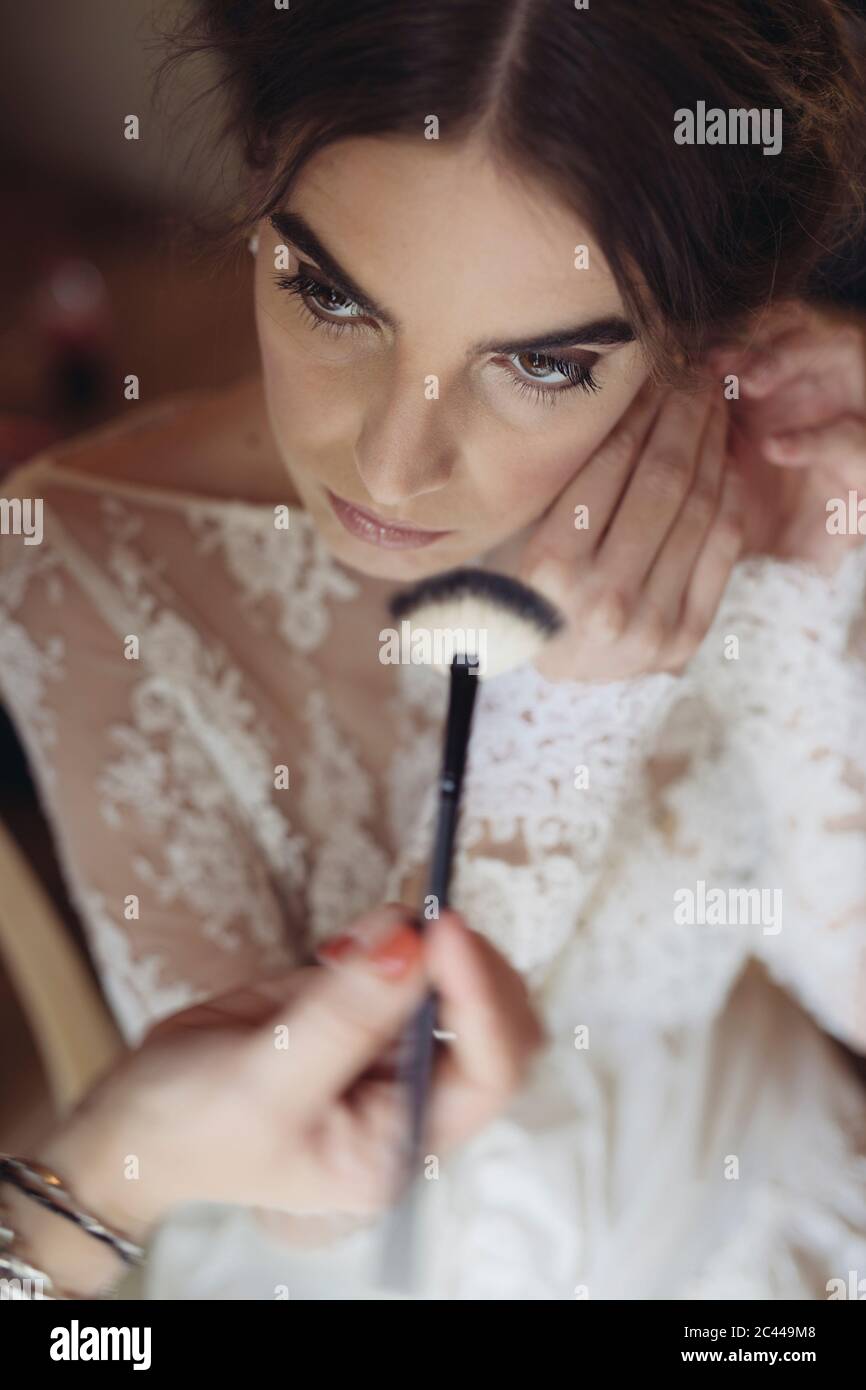 Hands applying cosmetics on face of bride Stock Photo