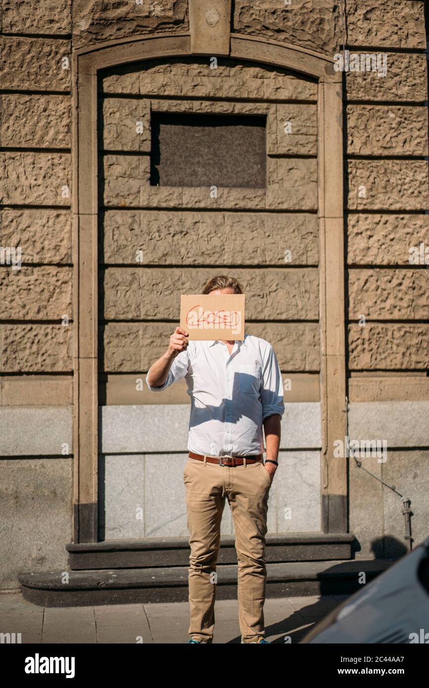 Shopkeeper holding cardboard with closed announcement in the city Stock Photo