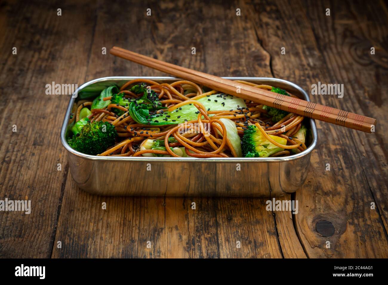 Lunch box of soba noodles with bok choy, broccoli, soy sauce and black