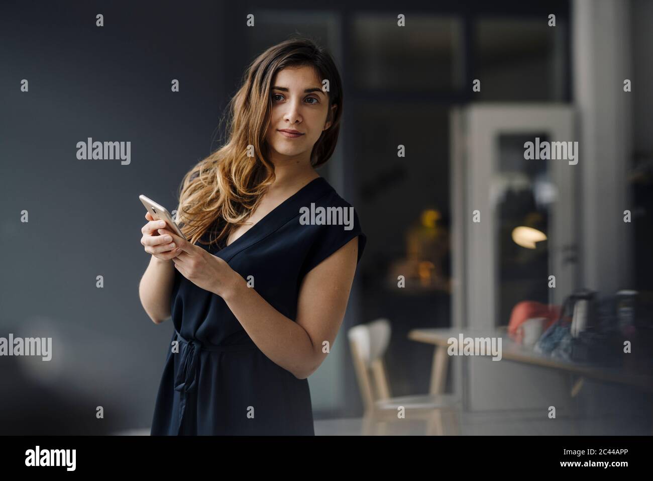 Portrait of young businesswoman with smartphone watching something Stock Photo