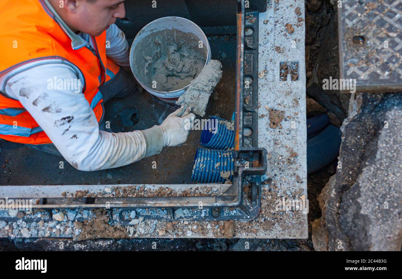 construction worker is repairing a pit of the data transmission line with optical fibers