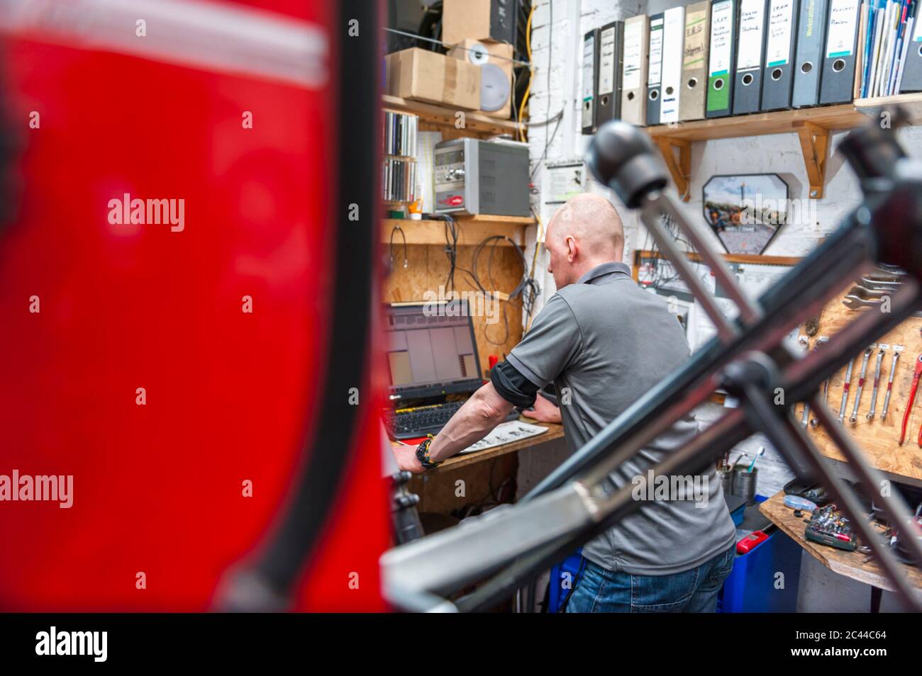 Bicycle mechanic working in bike shop using computer Stock Photo