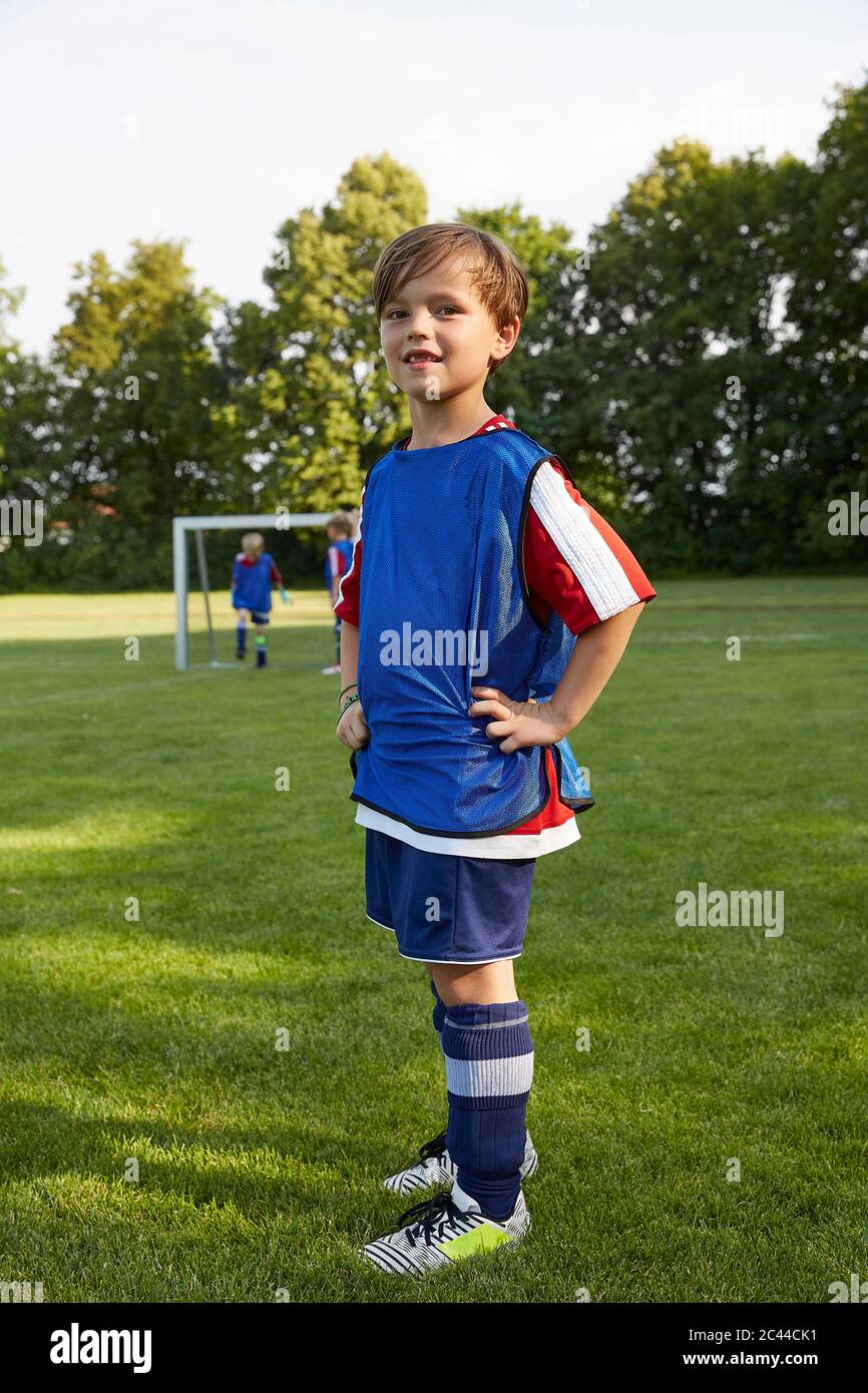 Portrait of confident soccer boy with hands on hips standing on field Stock Photo