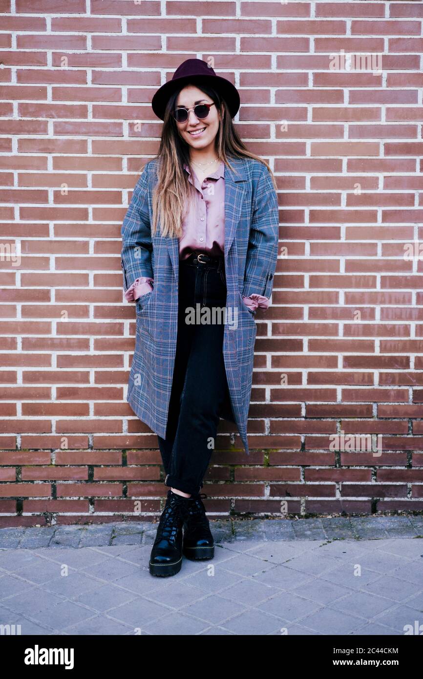 Portrait of fashionable woman standing in front of brick wall Stock ...