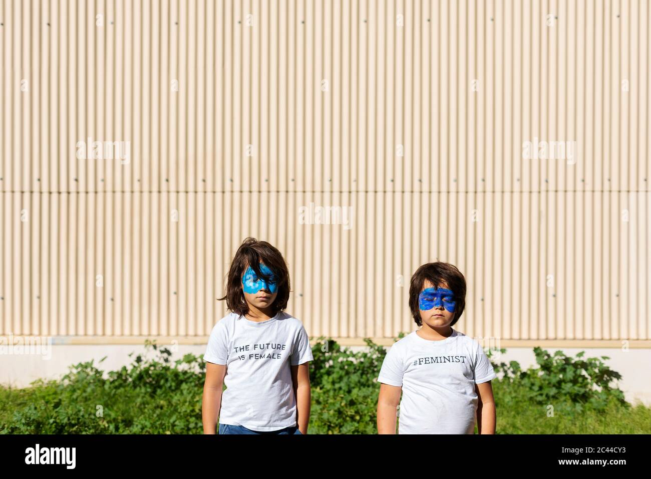Two brothers with painted blue masks on their faces wearing t-shirts with feministic imprints Stock Photo