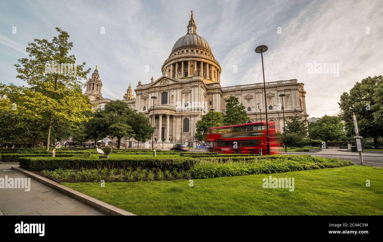 A view of St Pauls Cathedral in central London in the morning. A red bus can be seen going past. Stock Photo