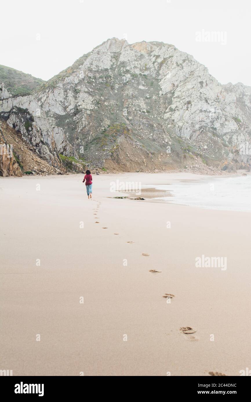 Woman leaving footprints while running at Ursa Beach, Lisboa Region, Portugal Stock Photo