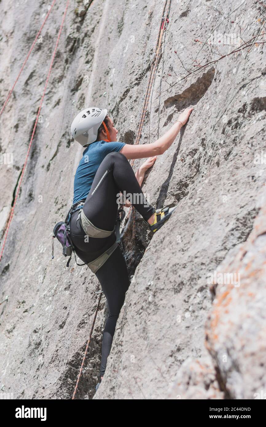 Woman rock climbing on sunny day Stock Photo