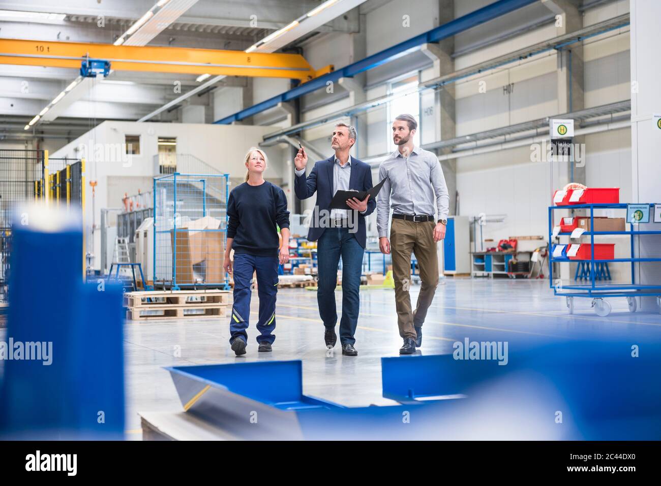 Two men and a woman walking in a factory Stock Photo - Alamy