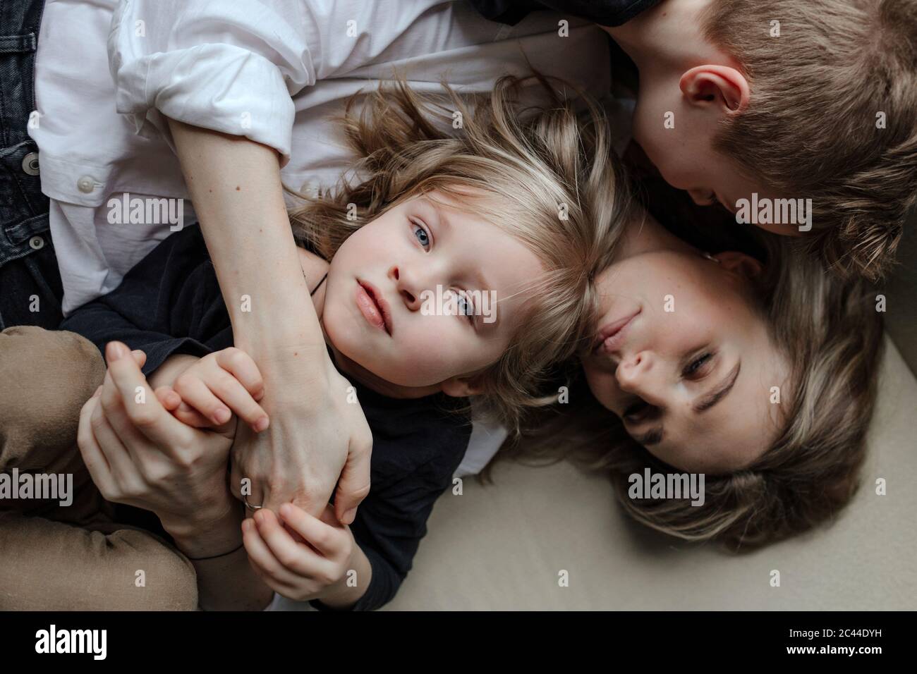 Directly above view of blond boy lying with brother and mother on sofa at home Stock Photo