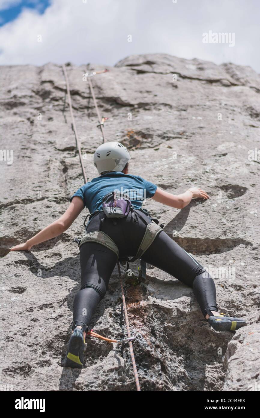 Young woman climbing rock with rope on sunny day Stock Photo