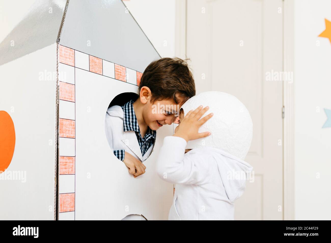 Siblings playing astronaut and researcher at rocket Stock Photo