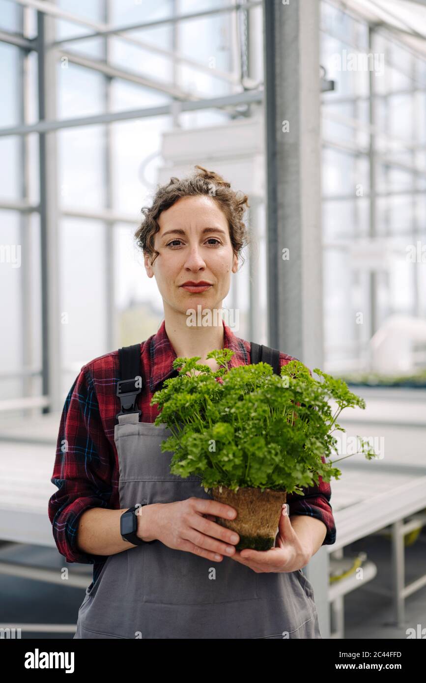 Portrait of woman holding parsley plant in greenhouse of a gardening shop Stock Photo