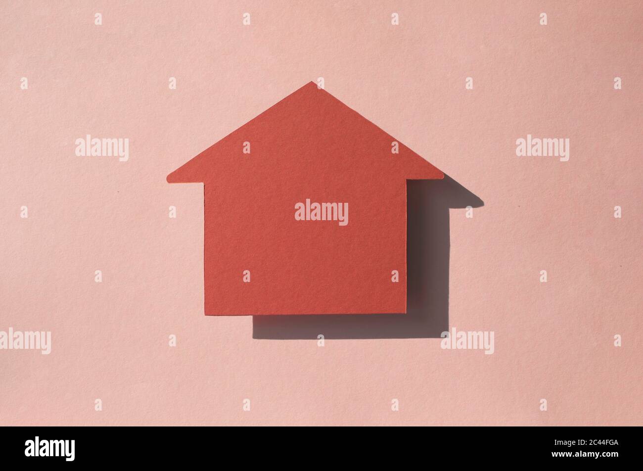 Studio shot of house shaped paper cut against pastel pink background Stock Photo