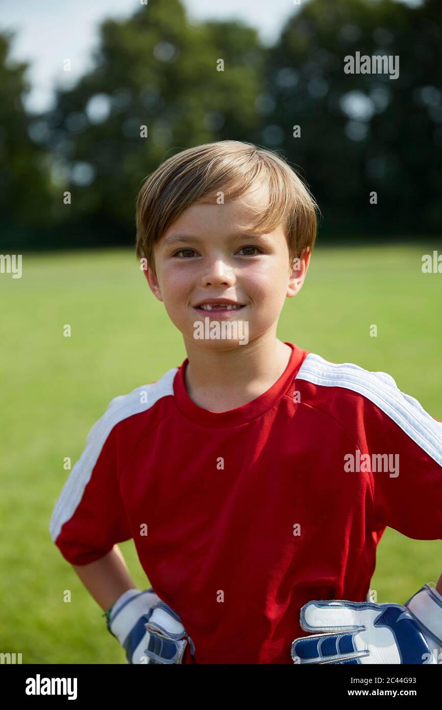 Portrait of happy boy in soccer uniform standing on field Stock Photo