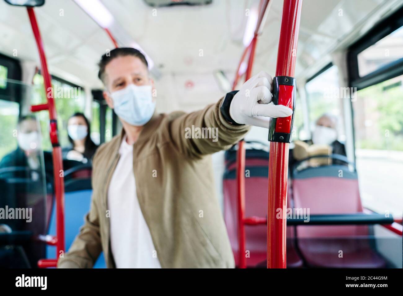 Man wearing protective mask gloves public bus pressing stop button hi