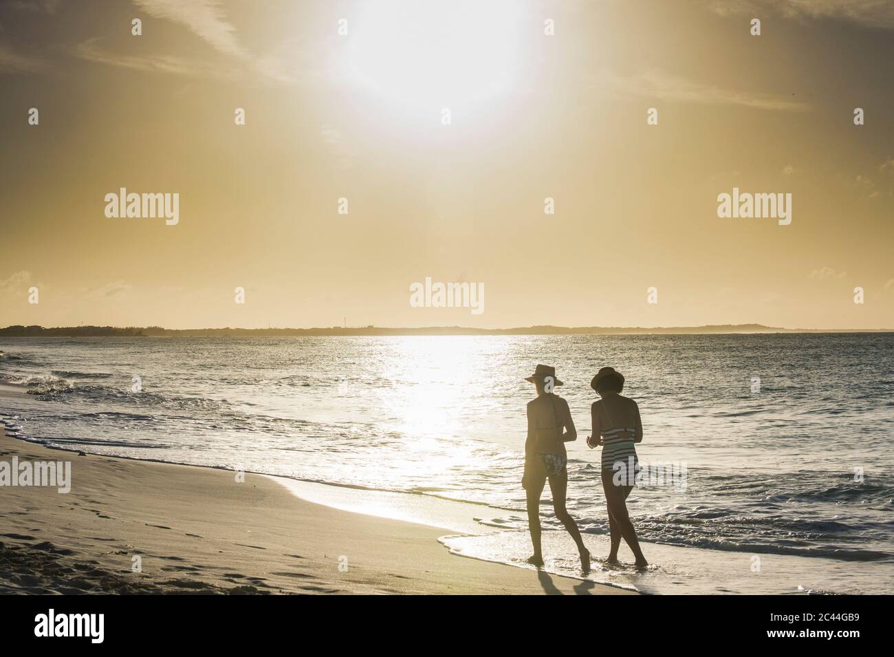 Rear view of female friends walking at Grace Bay beach during sunset, Providenciales, Turks And Caicos Islands Stock Photo