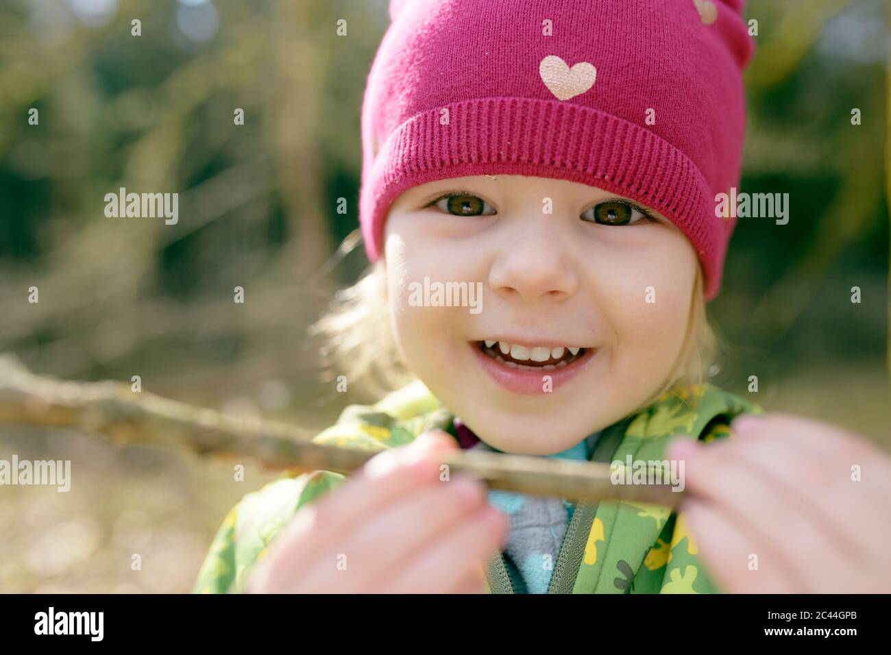 Portrait of smiling little girl with bough in nature Stock Photo