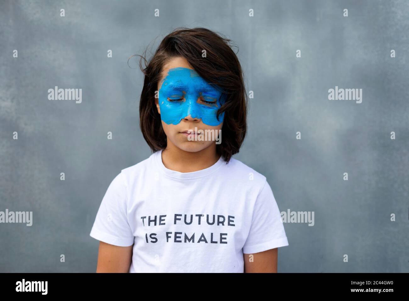 Portrait of boy with painted blue mask on his face wearing t-shirt with imprint 'The Future is Female' Stock Photo