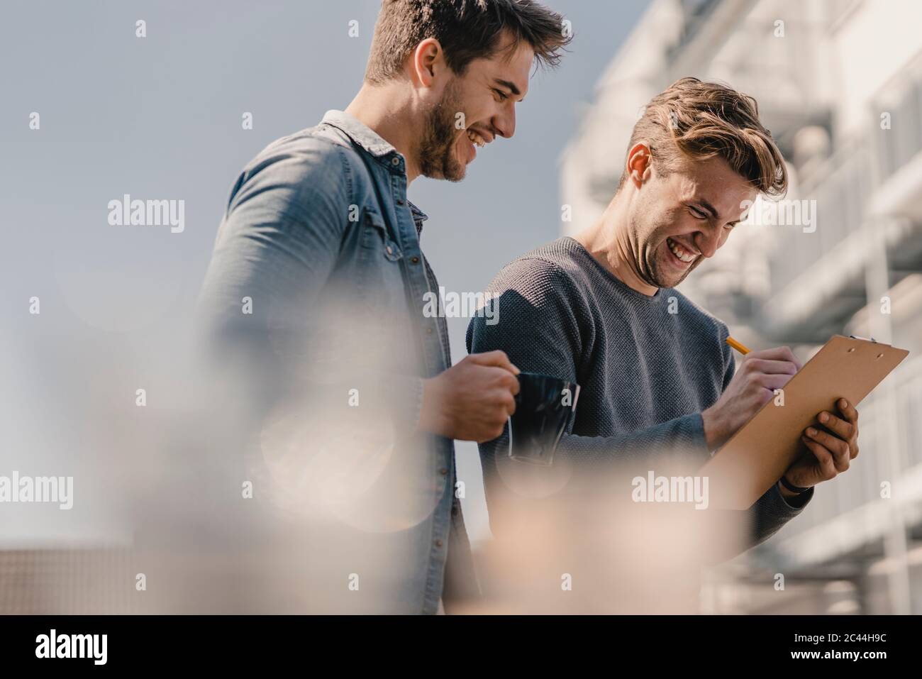 Colleagues brainstorming on balcony, writing down their ideas Stock Photo