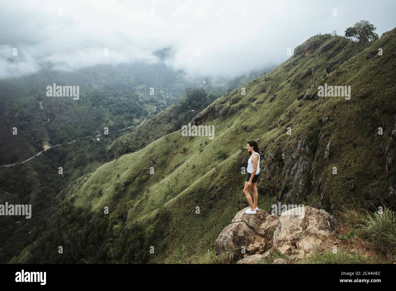 Sri Lanka, Uva Province, Ella, Female hiker standing on boulder at Little Adams Peak Stock Photo
