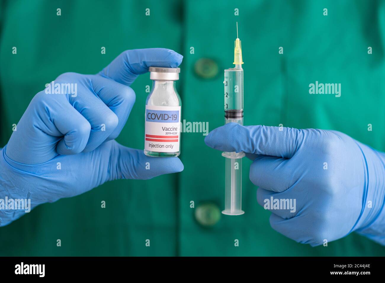 Woman in protective wear holding covid-19 vaccine and syringe Stock Photo