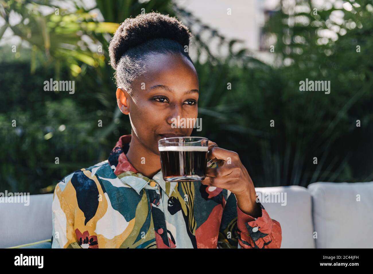 Portrait of young woman drinking black coffee in garden Stock Photo