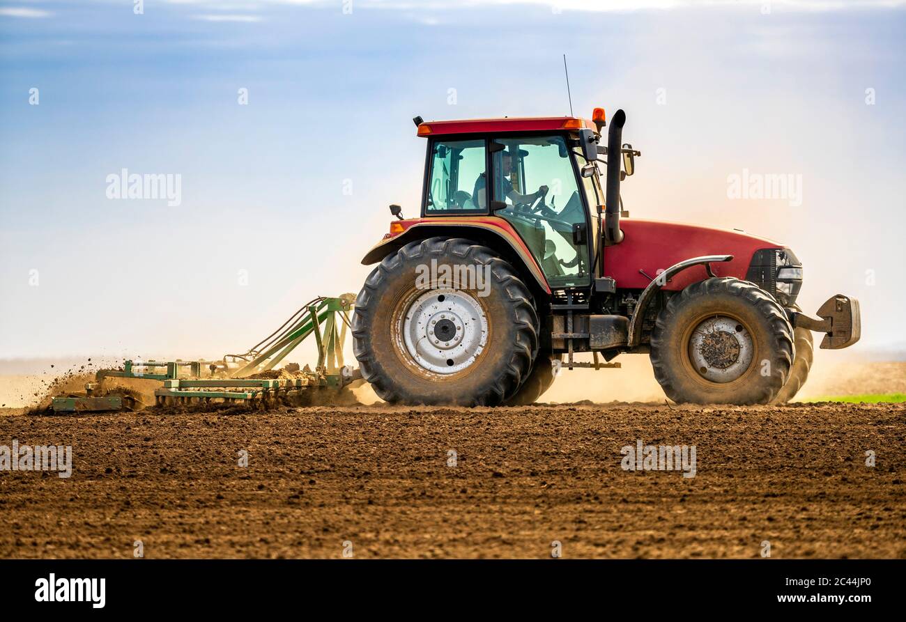 Farmer in tractor plowing field in spring Stock Photo - Alamy
