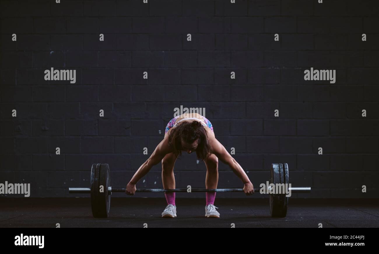 Young woman practicing barbell squat at gym Stock Photo