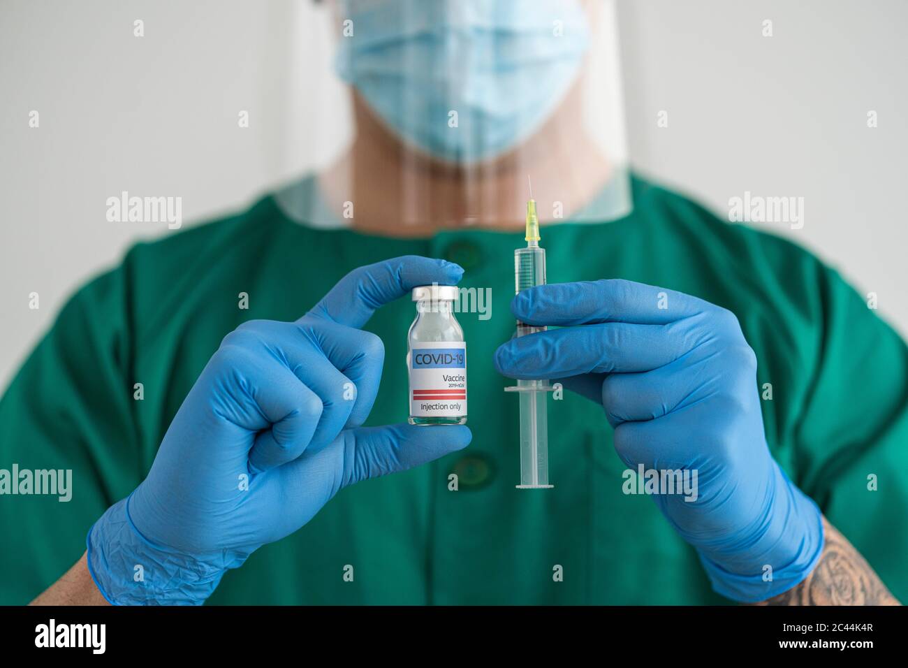Man in protective wear holding covid-19 vaccine and syringe Stock Photo