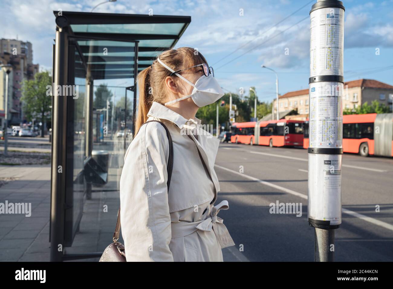 Woman wearing face mask checking schedule of public transport in the