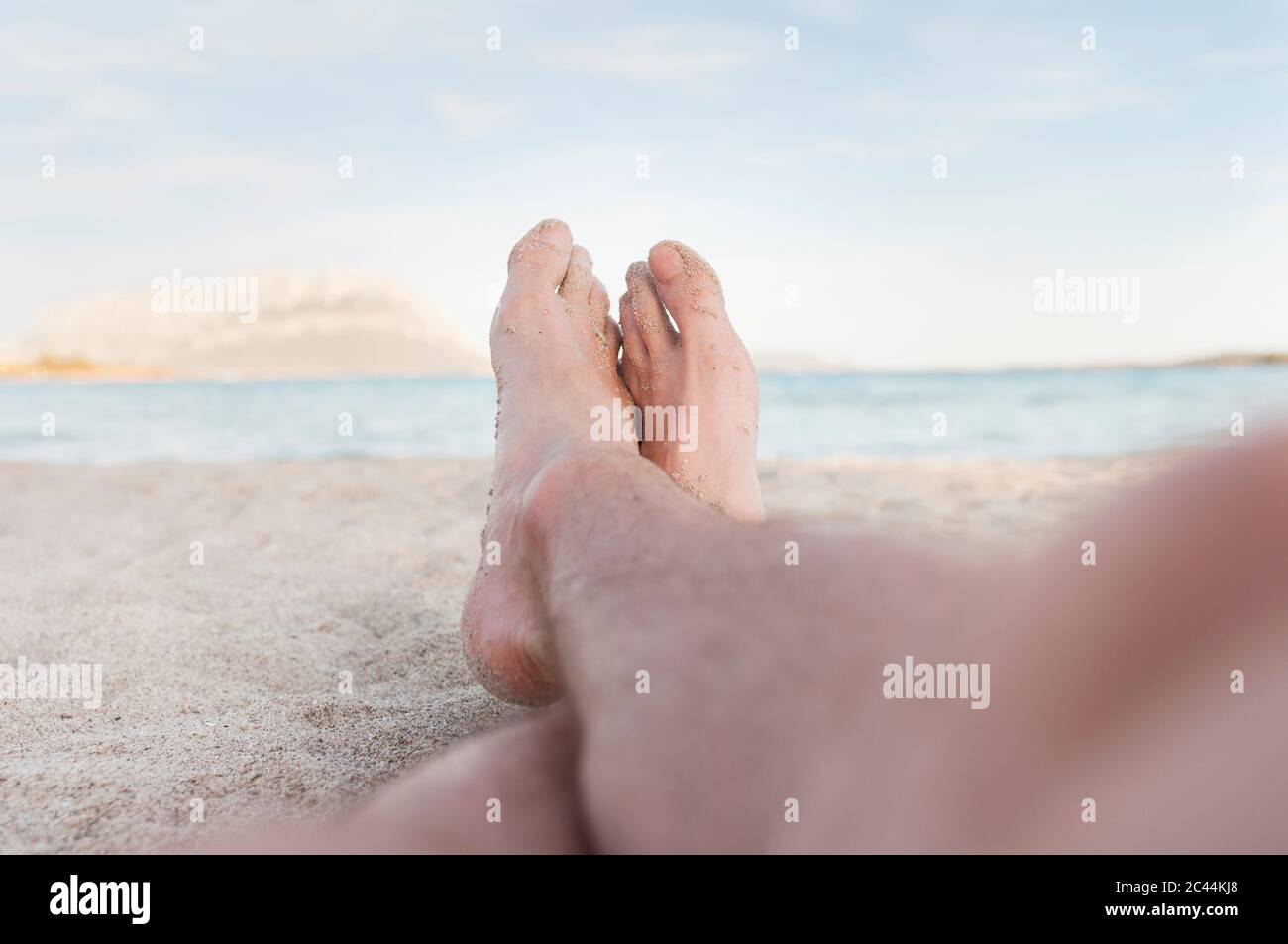 Man's sandy feet on the beach,  Sardinia, Italy Stock Photo