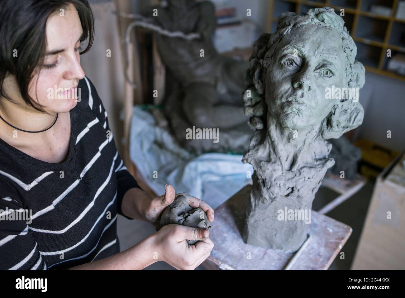 Female student forming clay for bust Stock Photo